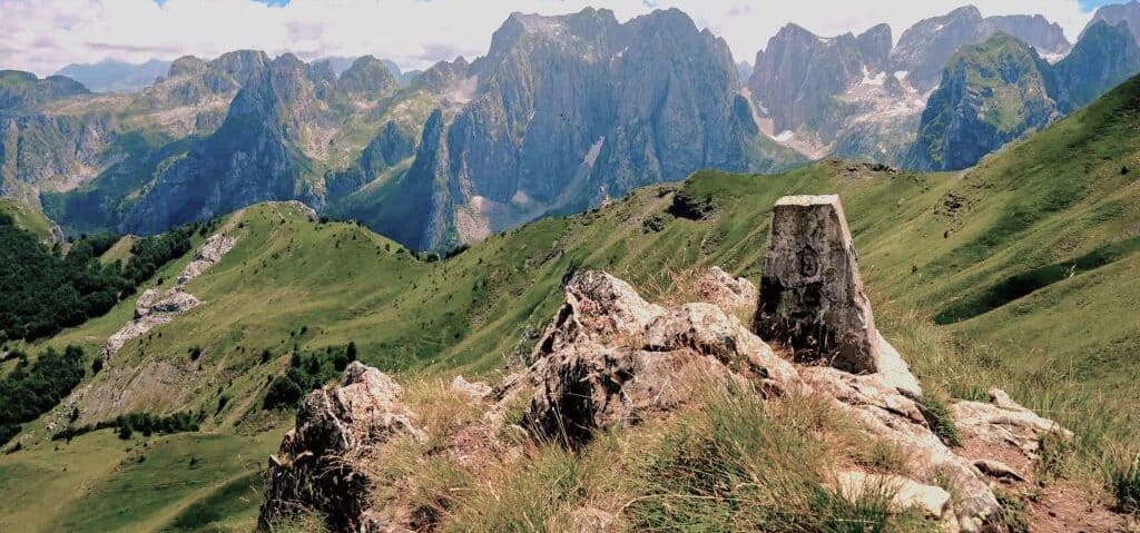 Gränstillstånd - Gränssten på Pekas of the Balkans Trail med bergstoppar i bakgrunden