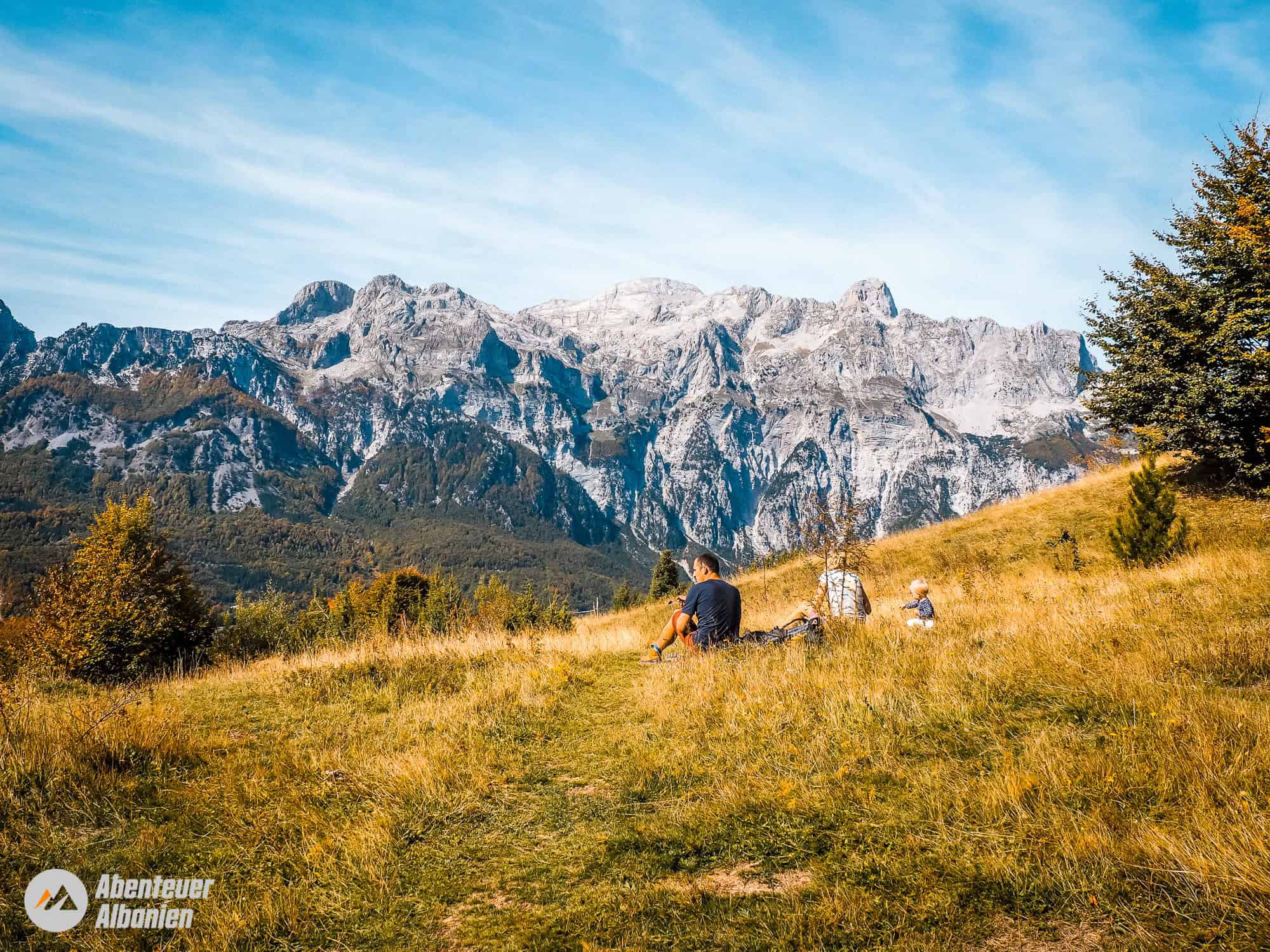 Hikers relax on a meadow in front of high peaks